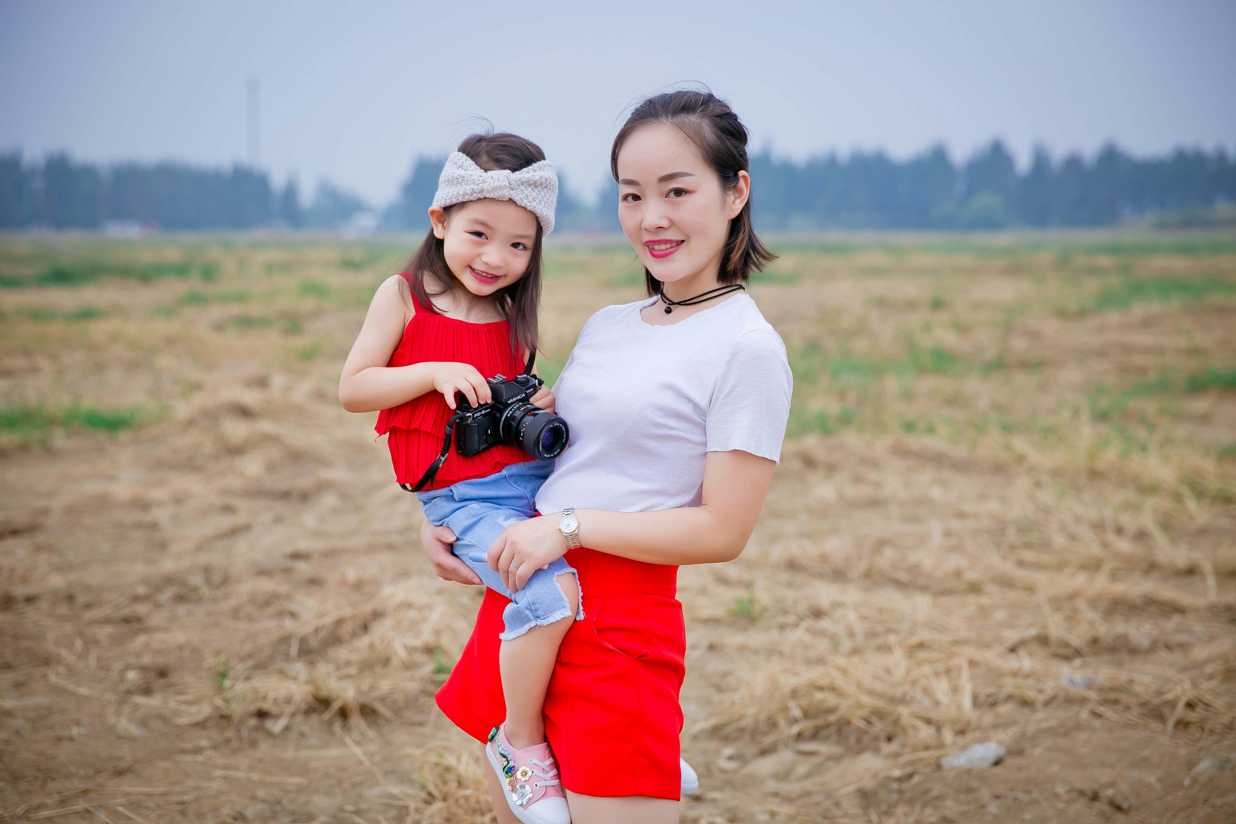 a person holding a camera and a girl kneeling on the ground